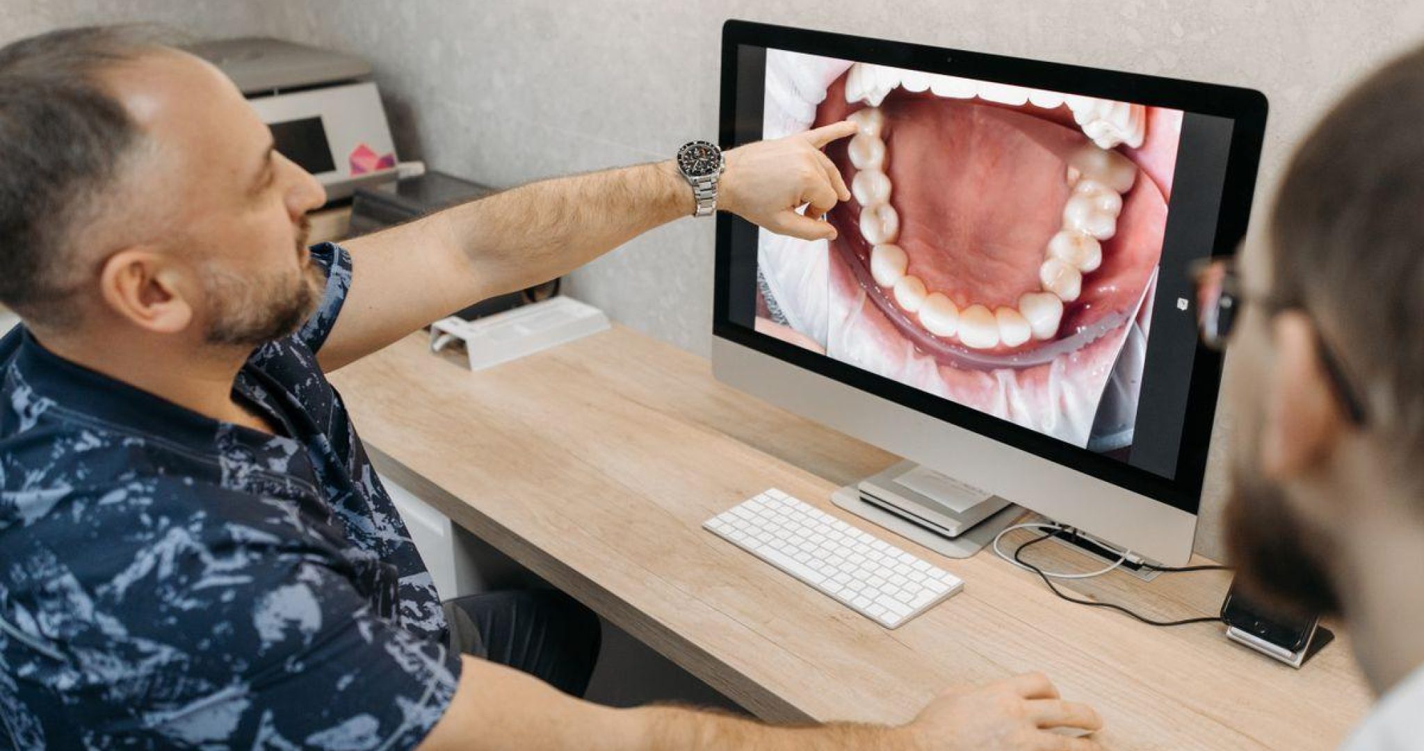 A dentist explaining dental conditions using images on a computer screen, representing modern dental technology