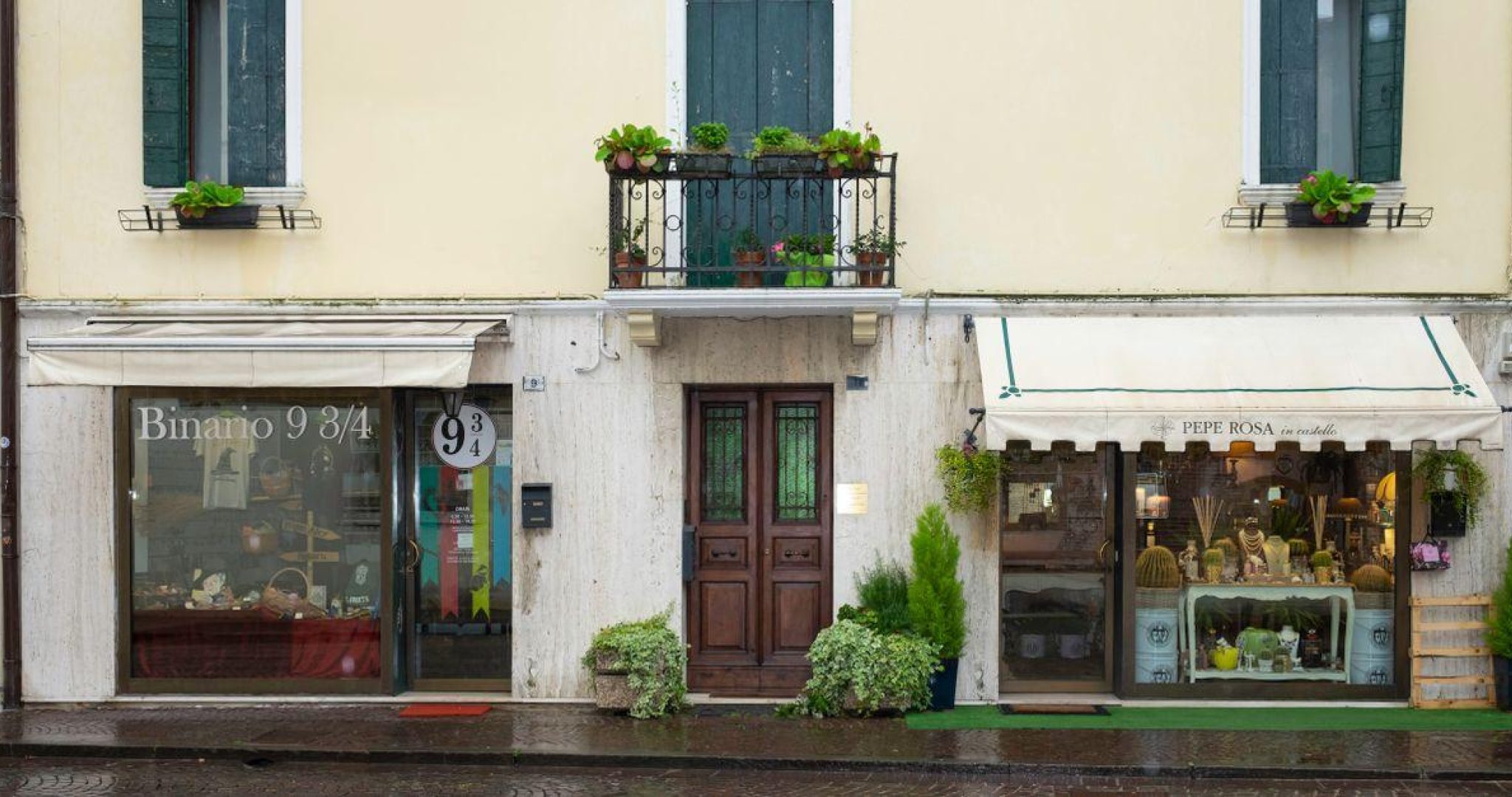 Quaint European boutique shops with elegant balconies and vibrant displays along a cobblestone street