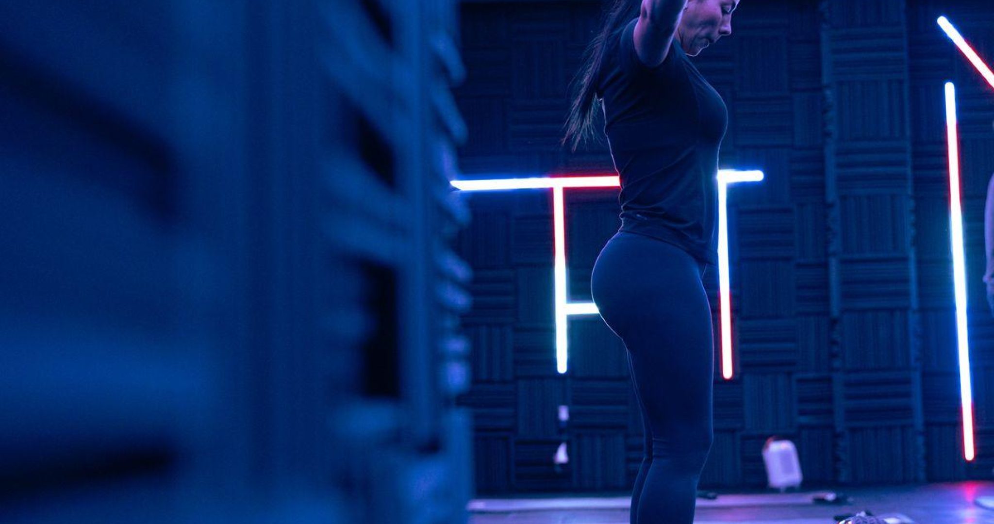 Person exercising in a modern fitness studio with neon lights