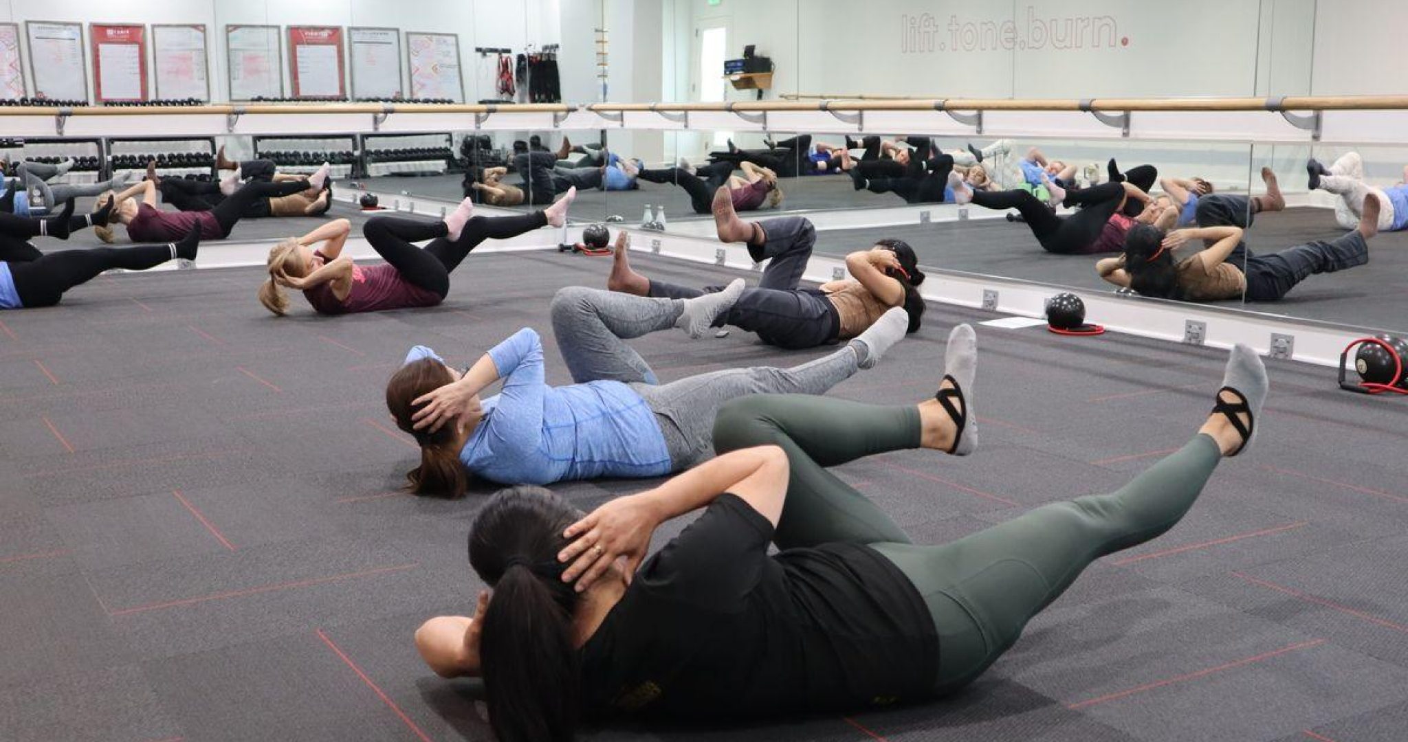 Group of adults participating in an indoor fitness class with core strength exercises