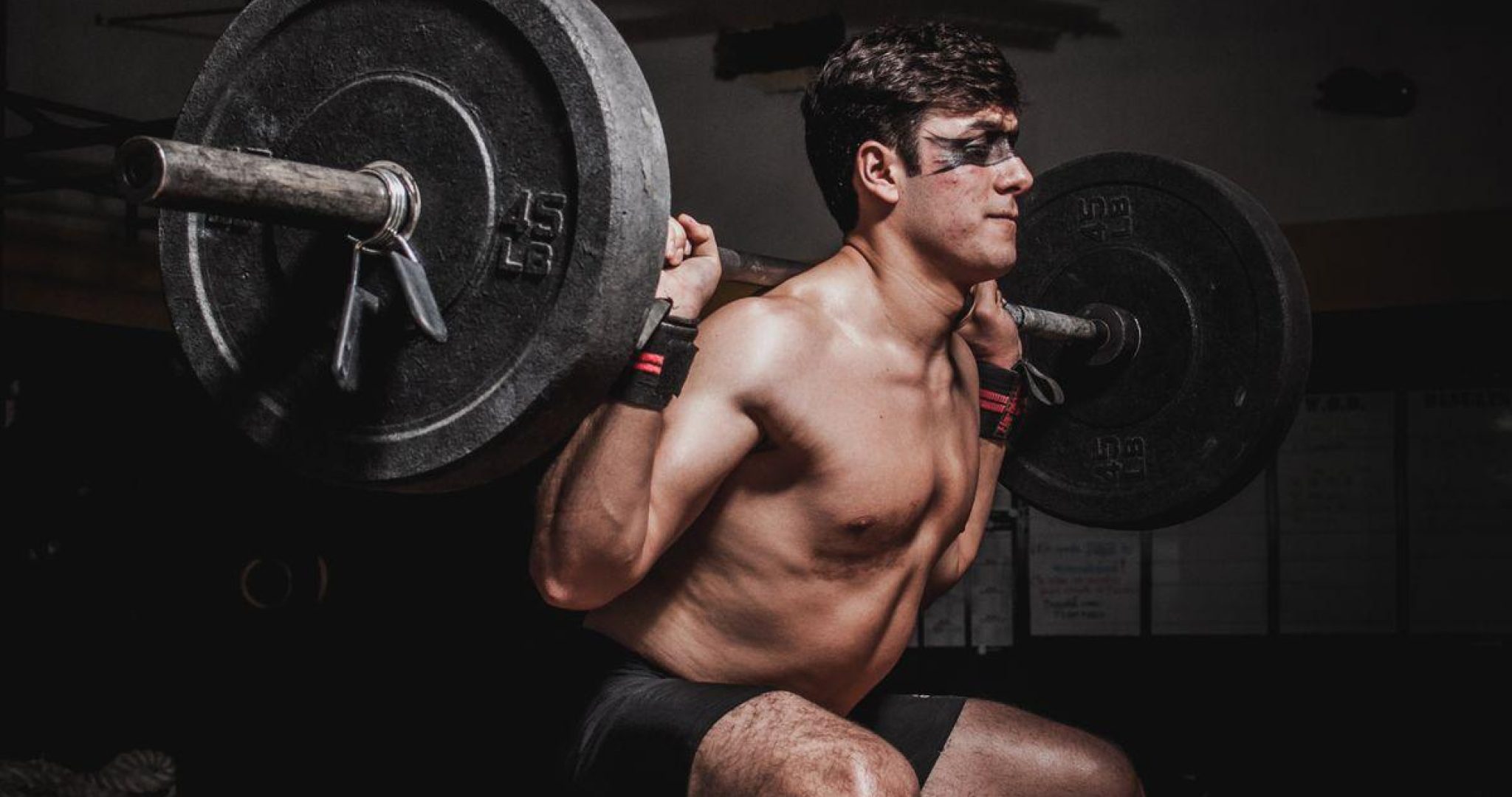Athlete performing a barbell squat in a modern gym, showcasing strength training