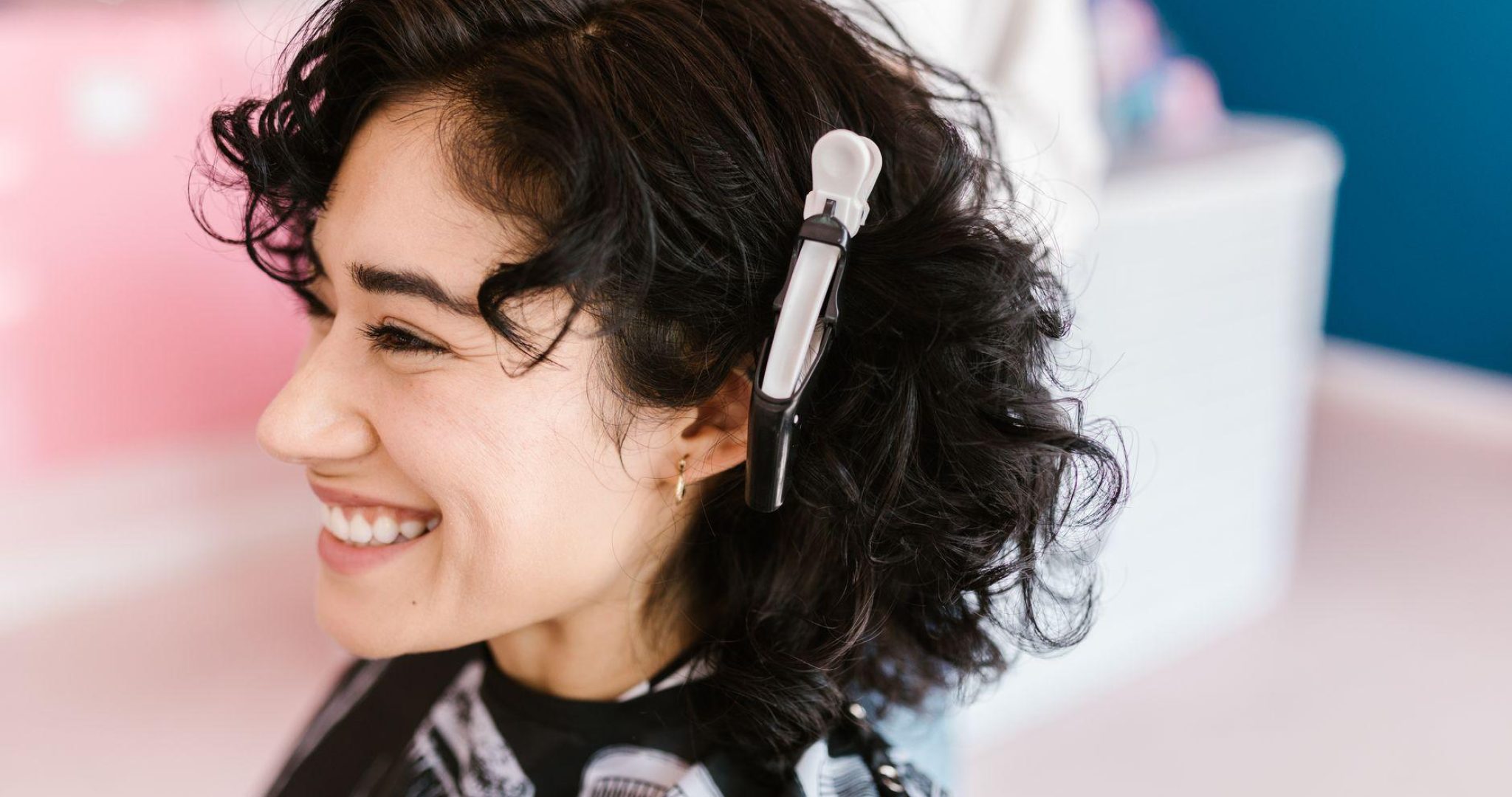 Woman with curly hair smiling in a modern hair salon