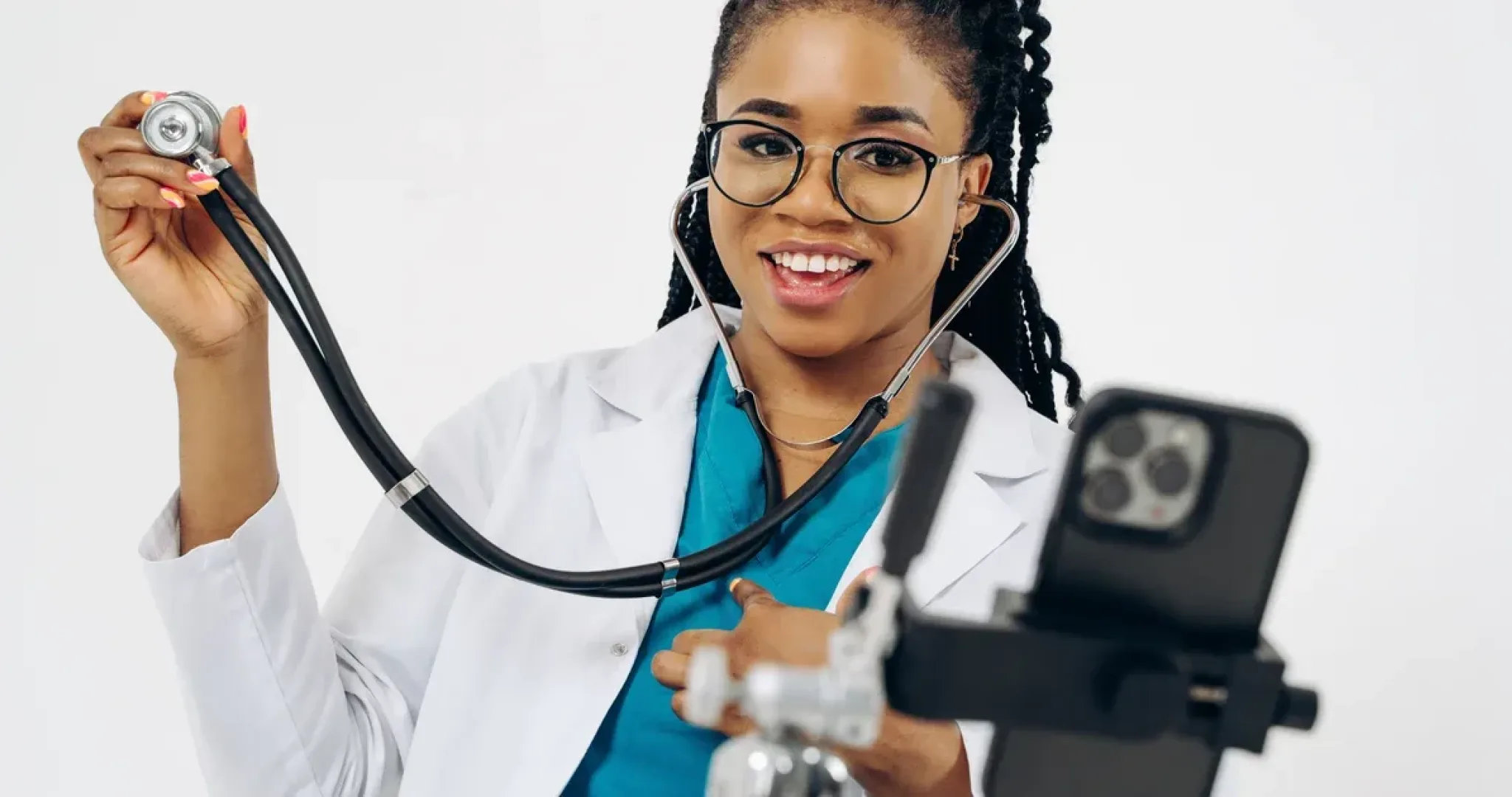 Young female doctor smiling while recording with smartphone and stethoscope