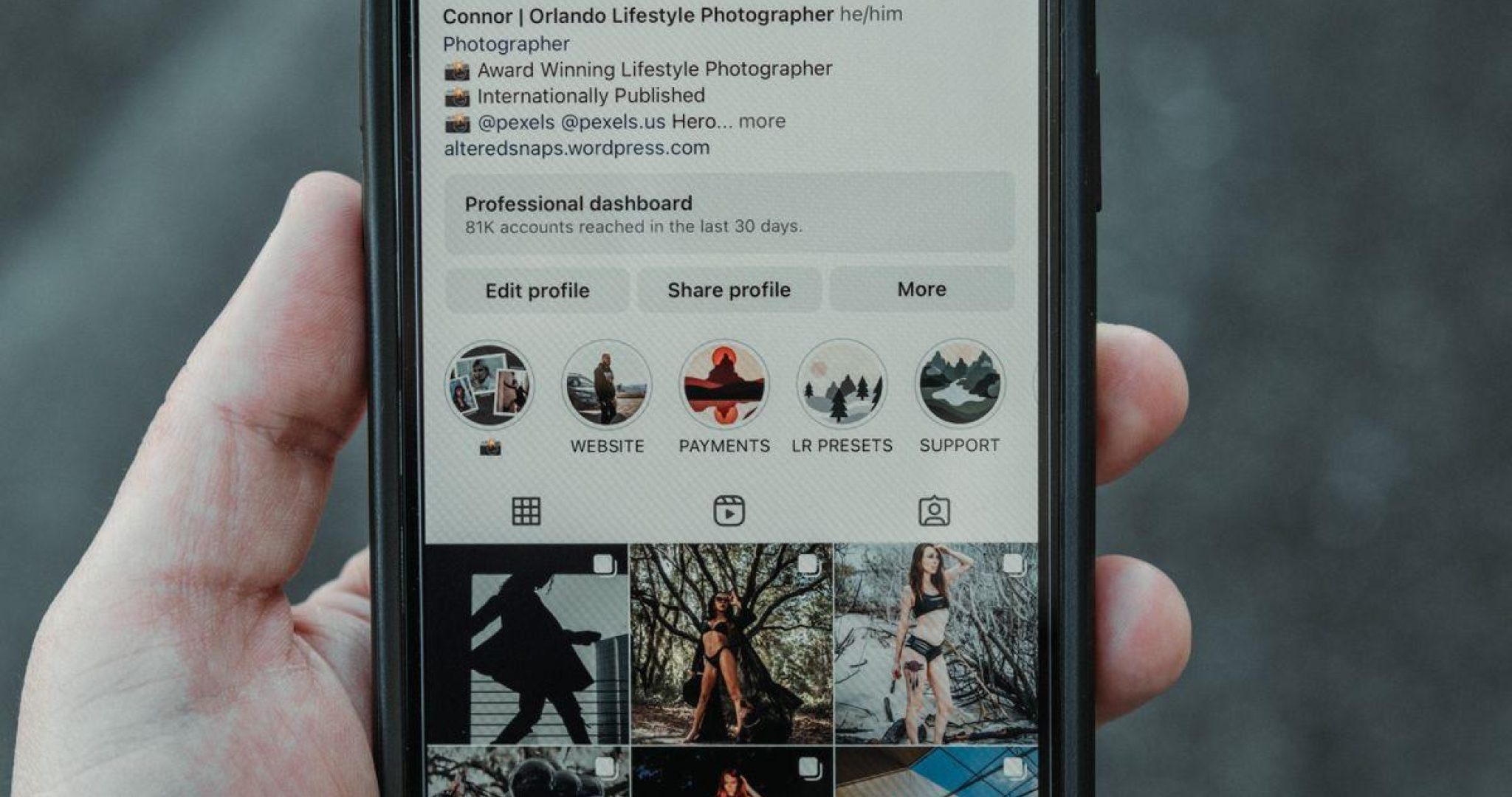 Hand holding a smartphone displaying an Instagram profile outdoors