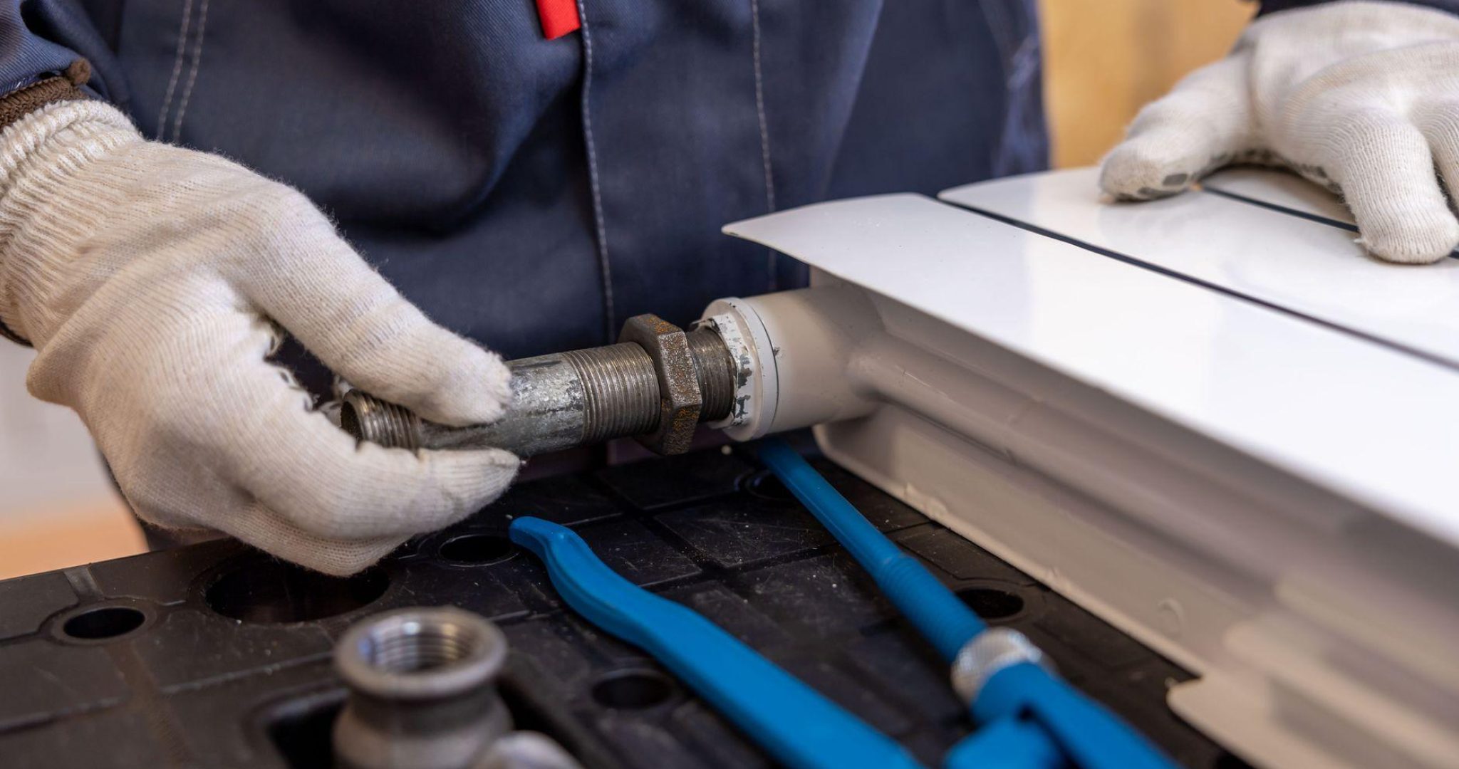 Plumber installing a radiator pipe using specialized tools