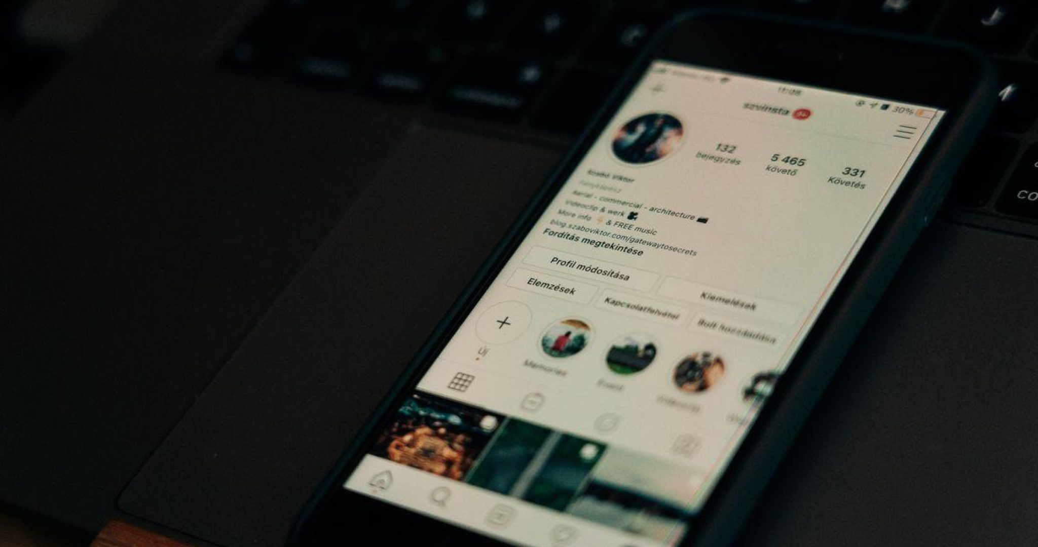 Smartphone displaying social media profile screen next to an open laptop